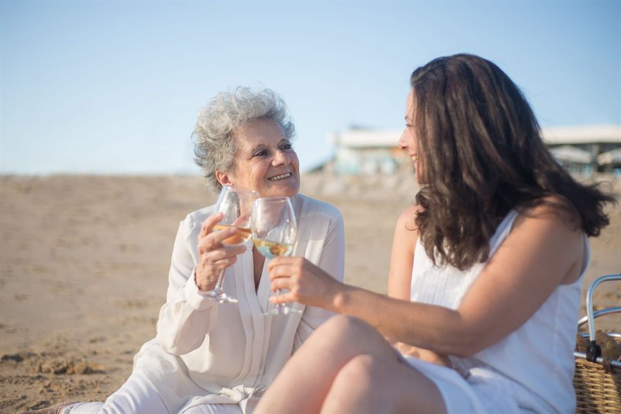 An older woman and a younger woman toasting with wine on a beach