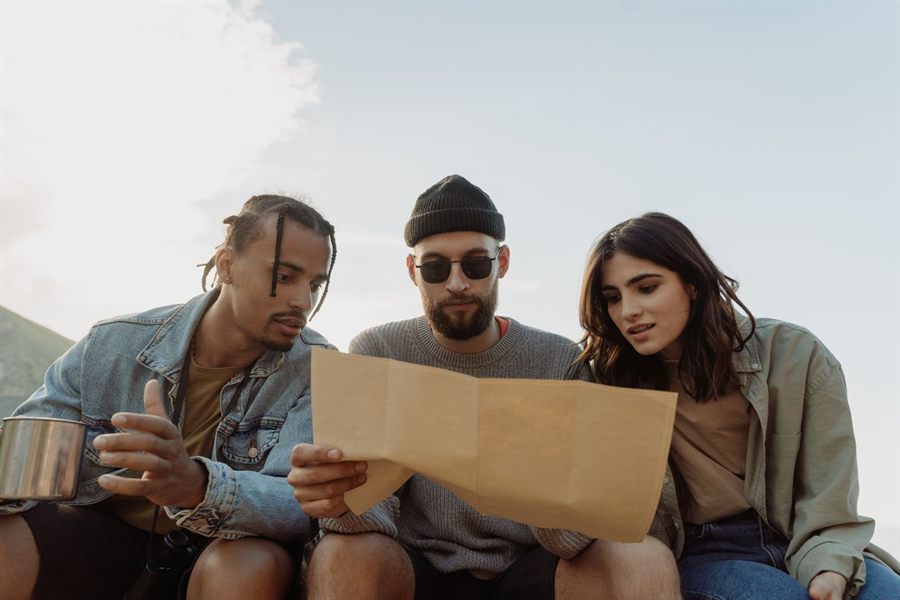 Three friends studying a paper map together outdoors