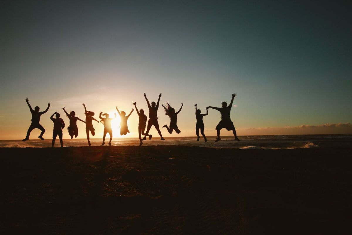 Silhouettes of a group of friends jumping on a beach at sunset