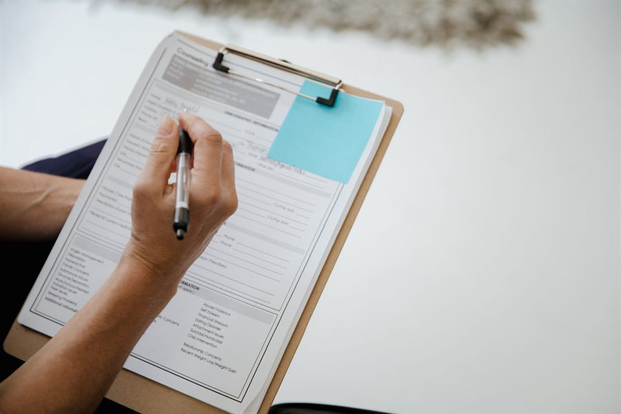 A person ticking boxes on a questionnaire held on a clipboard