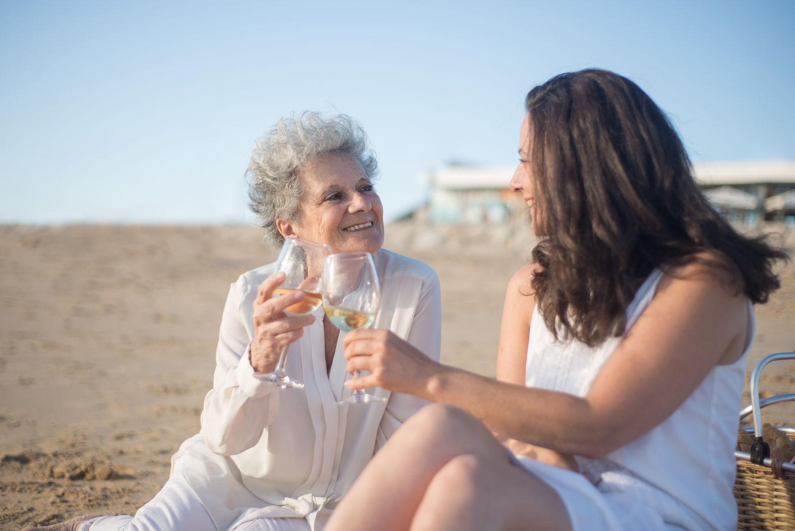 Two women toasting with wine on a beach, the kind of moment a customer satisfaction survey hopes to capture