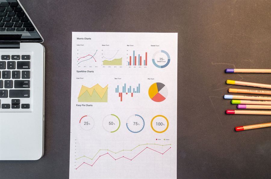 Printed charts and coloured pencils next to a laptop