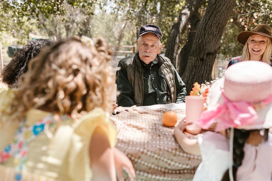 A family of several generations laughing together around an outdoor table