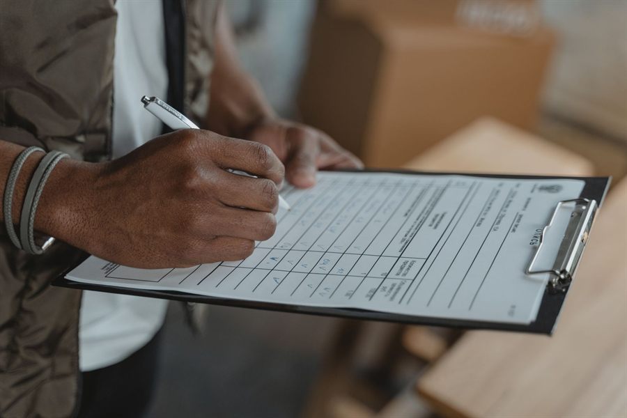 Close-up of a hand filling in a form on a clipboard